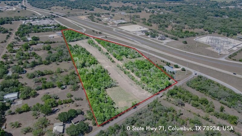 Aerial drone view of about 19 wooded and cleared acres outlined in red beside Highway 71 and its frontage road in Columbus, TX
