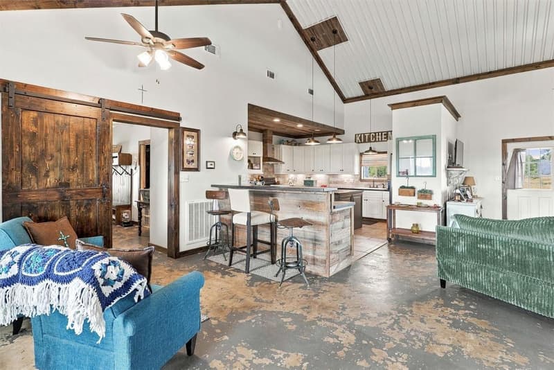 Open family room flowing to a kitchen with a wood-clad breakfast bar, pendant lights and a sliding barn door