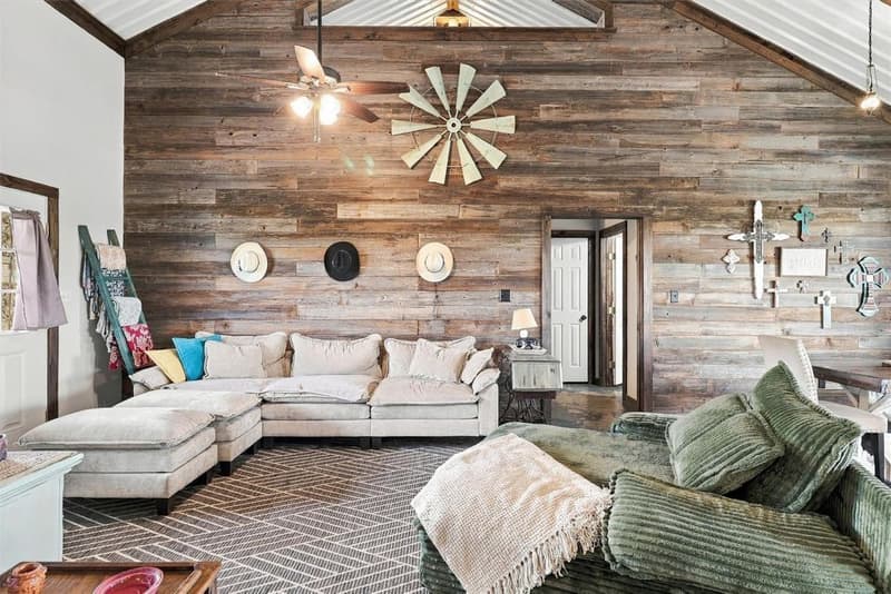 Living room with a large light sectional, wood-plank accent wall, windmill decor and a vaulted metal ceiling
