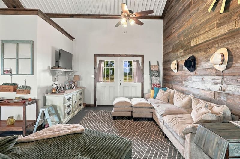 Living room with a sectional sofa, TV on a white wall, and French doors with window panes leading outside