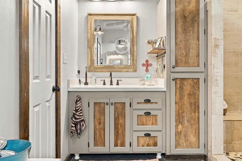 Separate bathroom vanity with gray cabinets, wood inset panels, framed mirror and tall linen cabinet