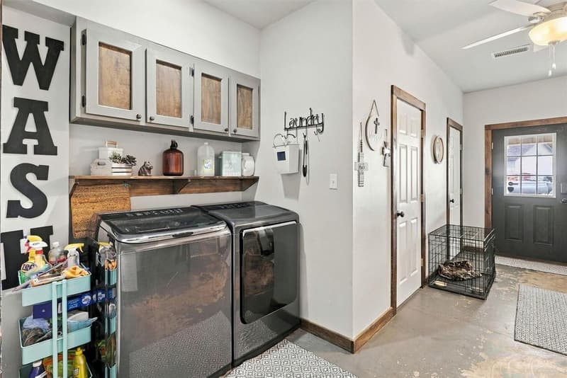 Laundry area with washer and dryer, open shelf, upper cabinets with wood panels and an exterior door with window