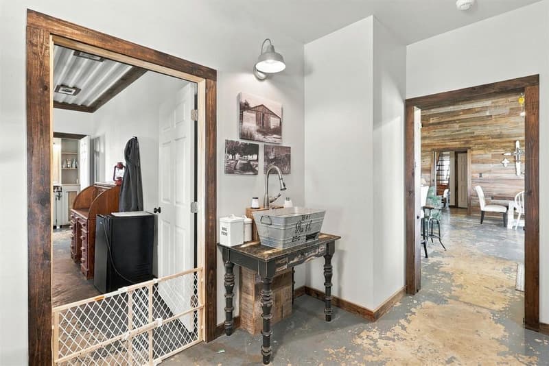 Hallway with galvanized tub vessel sink on a turned-leg table, barn light, and view into the great room
