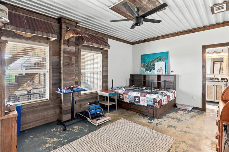 Bedroom with wood-plank window wall, corrugated metal awnings over windows, metal ceiling and black ceiling fan