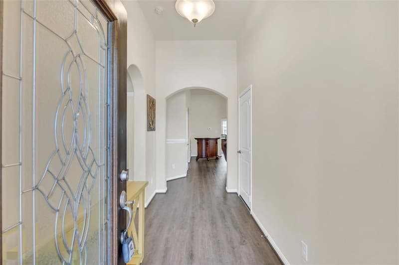 Hallway from the front door with vinyl plank flooring and arched openings leading toward the main living area