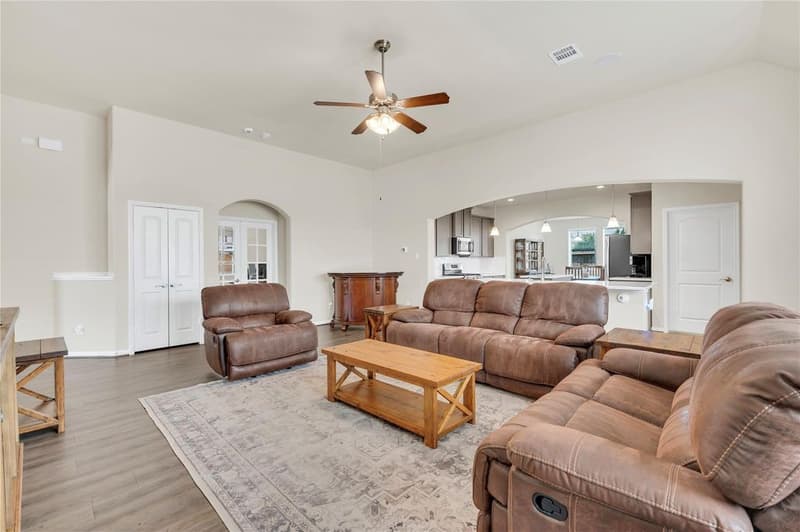 Family room with sloped ceiling and ceiling fan, open to the kitchen with stainless appliances and pendant lights