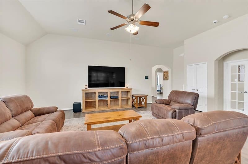 Family room with sloped ceiling, ceiling fan, wall-mounted TV and French doors to an adjoining room