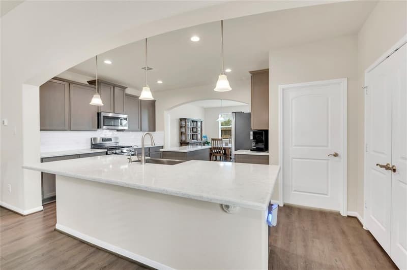 Kitchen with shaker cabinets, white subway tile backsplash, gas range, stainless microwave and large quartz island