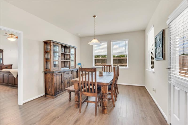 Dining area with pendant light, three windows, back door and vinyl plank flooring