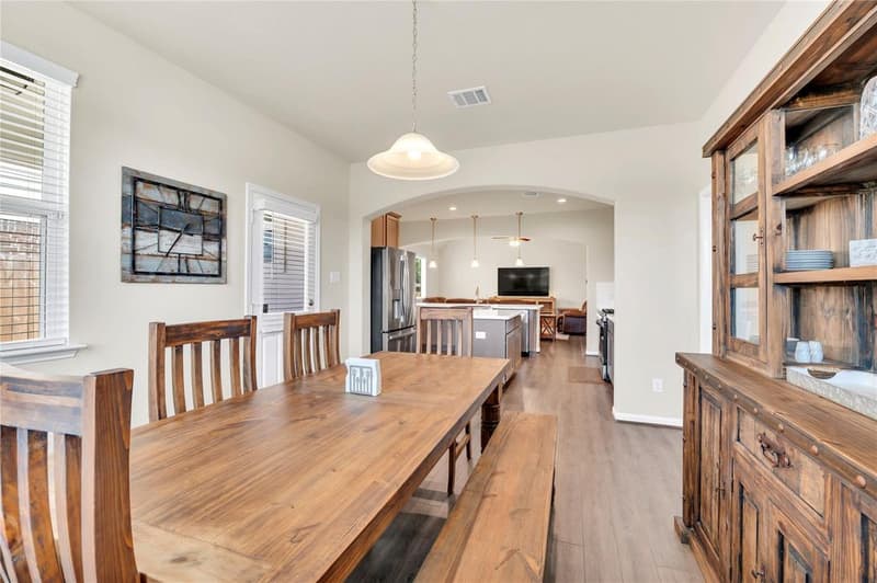 View from the dining area through an arched opening to the kitchen islands and living room