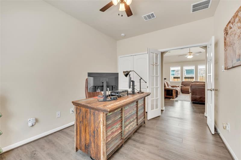 Home office with desk, double-door closet and French doors open to the living room