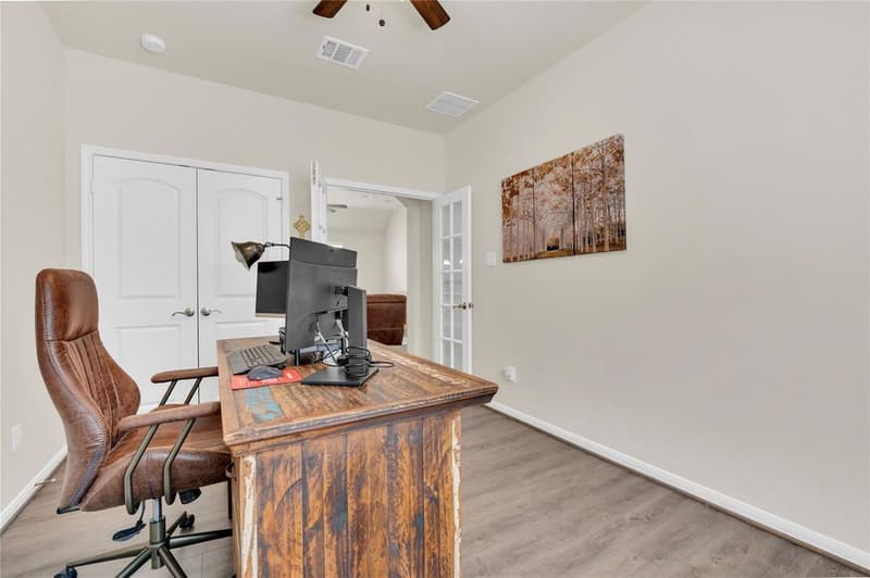 Home office with desk, leather chair, double-door closet and French doors