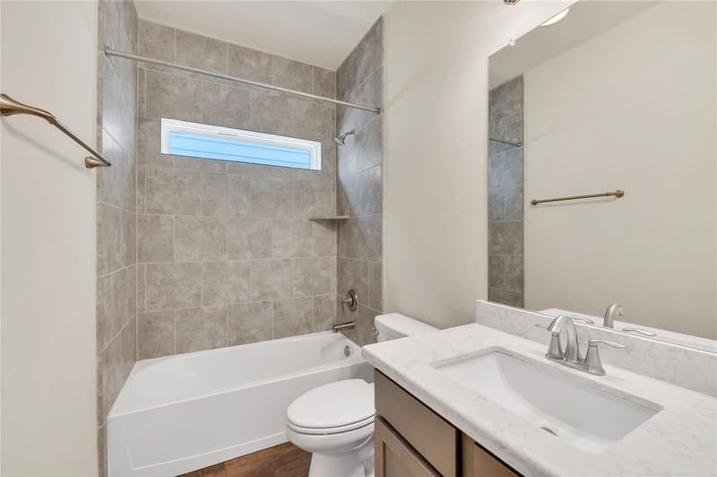 Secondary bath with tiled tub and shower combo, window, and single vanity with light countertop