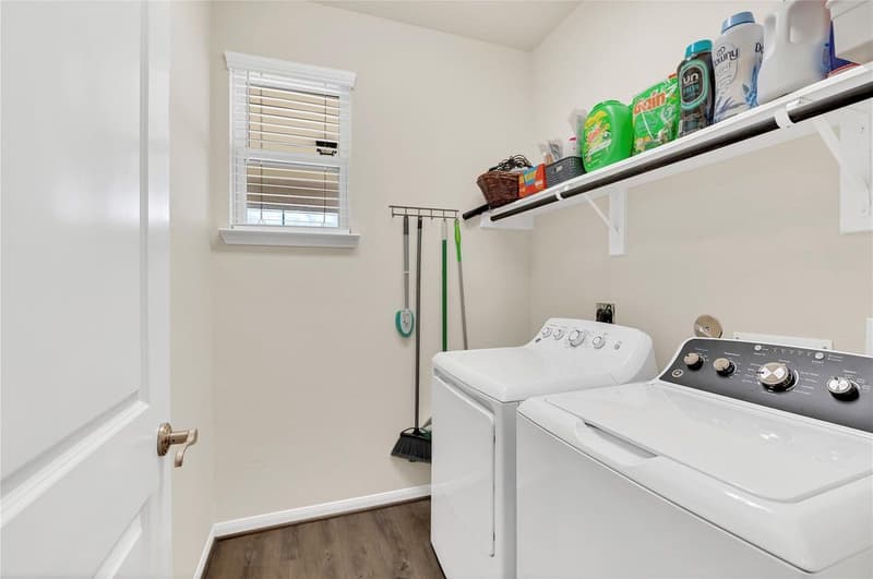 Laundry room with window, wood-look plank floor, wall-mounted shelf and washer and dryer