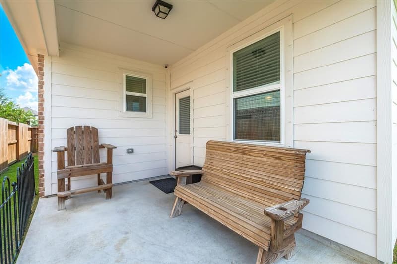 Covered back patio with ceiling light, rear door, window, wooden bench and Adirondack-style chair