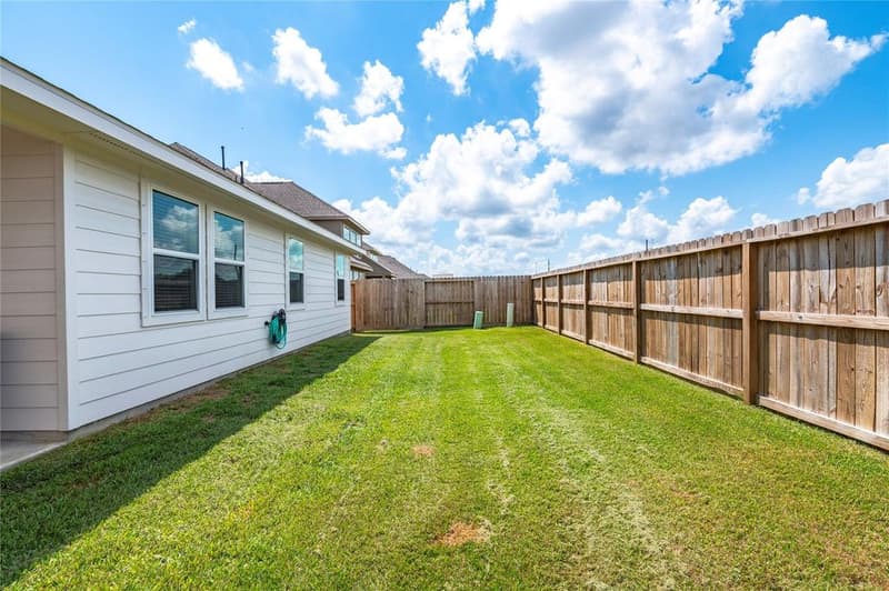 Side view along the home showing lawn running between the house and the wood privacy fence