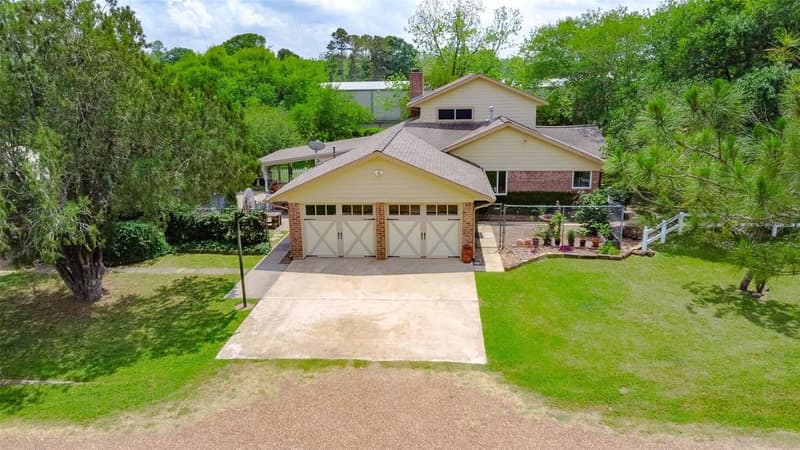 Two-story brick and siding home with a garage with two carriage-style doors, a concrete drive and a fenced side yard