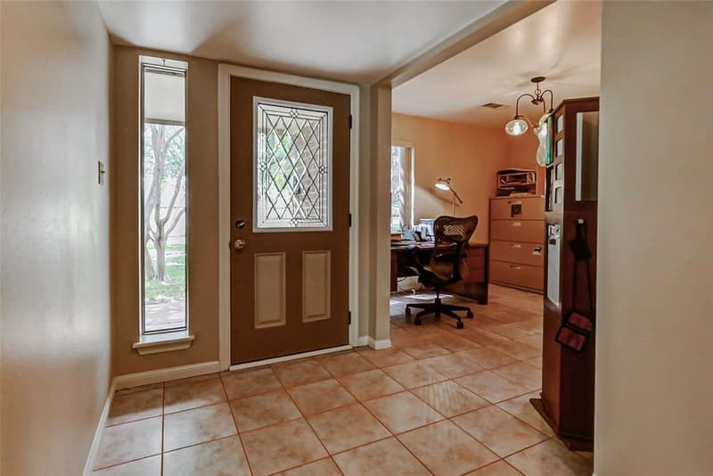 Tiled front entry with a leaded-glass front door and sidelight, opening into a home office with desk and file cabinets