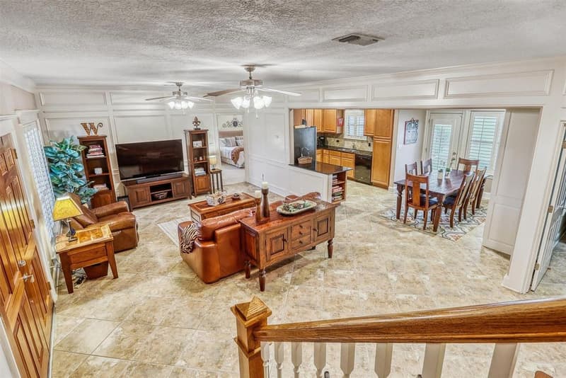 View from the staircase over a tiled open living area, kitchen peninsula and dining area with French doors