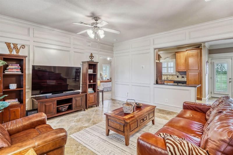Living room media wall with paneled wainscoting, open to the kitchen and a glass door to the backyard