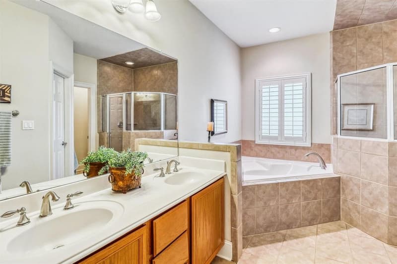 Primary bath with double-sink vanity, large mirror, corner soaking tub and a glass-enclosed shower